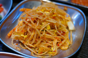 Seasoned bean sprouts are provided on stainless steel plates.