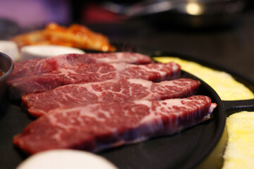 Red raw meat is being baked on an iron plate.