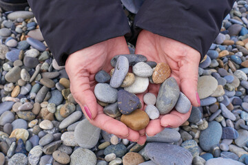The old woman stuffed her hands with colorful pebbles from the pebbly beach.