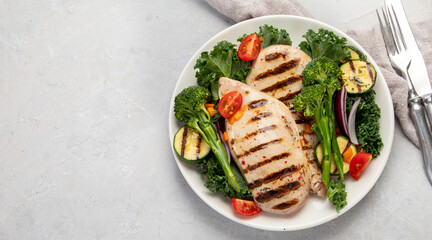Grilled chicken with vegetables on light background.