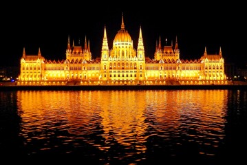 the illuminated  neo-gothic hungarian parliament building as seen at night from the danube river on...