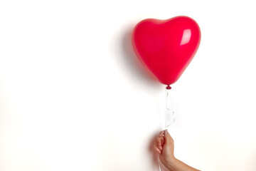 Inflatable helium balloon in the shape of a heart for Valentine's Day are held by a girl in her...