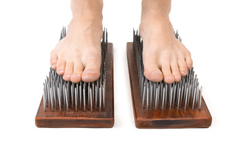 Male bare feet stand on a Yoga desk with sharp nails, close up, front view, isolated on white.