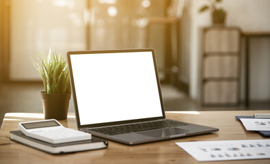 Mockup laptop computer with white screen put on desk table of business office.