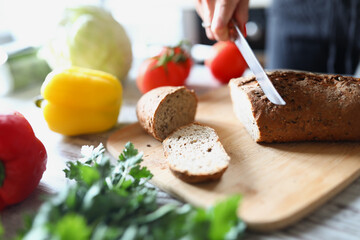 Female hands cut bread on the kitchen table