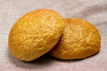 Two loaves of round bread on a background of fabric.