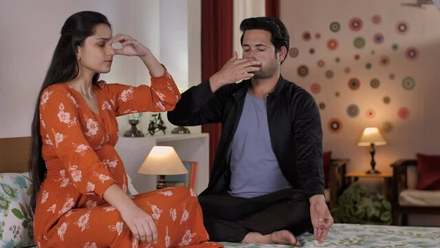 A beautiful pregnant wife and her husband practicing doing breathing exercises. A young Indian couple preparing for baby childbirth - family relationships  maternity  future parents