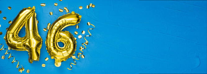 golden foil balloon number forty six. Birthday or anniversary card with the inscription 46. blue concrete background. Anniversary celebration. Banner.