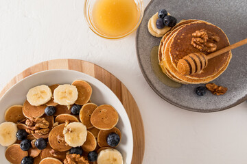 tiny pancakes - cute healthy breakfast - a new concept food trend. a great snack with fruits, berries, honey, milk. top view.