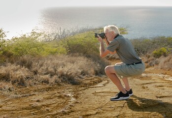 Old man enjoying nature and taking photos with his camera outdoor.
