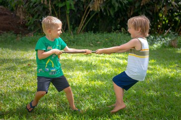 Two kids having fun outdoor, playing tug of war.