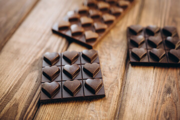 Delicious sweet pieces chocolate on wooden background shape of heart