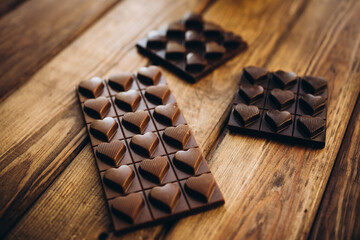 Delicious sweet pieces chocolate on wooden background shape of heart