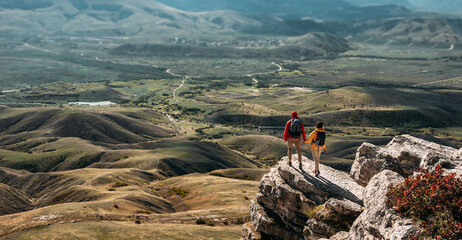 A man and a woman in tourist equipment are standing on a rock and admiring the panoramic view. A...