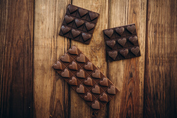 Delicious sweet pieces chocolate on wooden background shape of heart