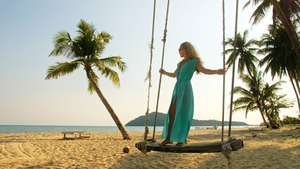 Silhouette woman spends her vacation at the seaside. The girl is swinging on a swing. Concept happy holidays, joy, lightness, fresh air, cleanliness and health