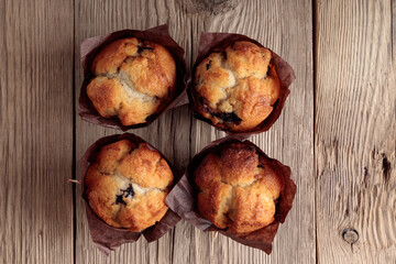 Top view of four homemade delicious muffins on wooden background. Copyspace.