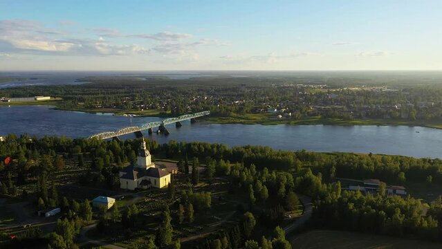 Aerial drone view passing the Alatornio church, towards Haparanda city, golden hour in Lapland