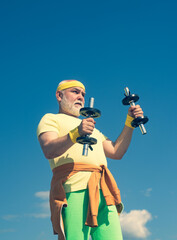 Health club or rehabilitation center for elderly aged pensioner. Senior sport man lifting dumbbells in sport center.