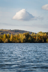 Lake with small waves on water surface in rural landscape. Cloud over the hill. Tranquil scenery