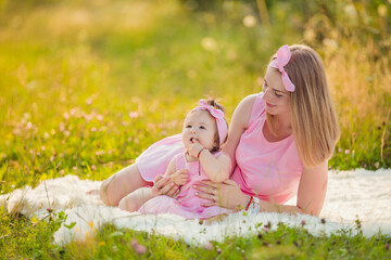 mother and daughter are sitting on a blanket in the summer garden