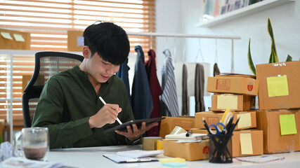 Young man working with digital tablet for online shopping at home office.