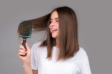 Young woman hairdresser with comb brushing hair. Brunette woman combing hair.