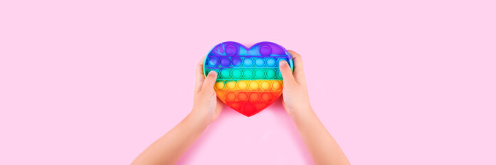 Banner with child's hands holding colored pop it anti-stress toy.