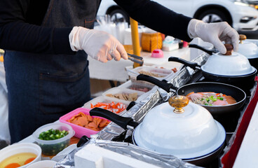 Man cooking eggs for breakfast, standing at the kitchen at on the side of the road