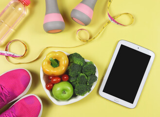 black blank screen computer tablet, vegetables and fruit in heart shape plate, bottle of water,...