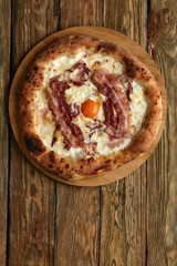 Carbonara pizza with bacon and egg on wooden background