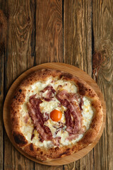 Carbonara pizza with bacon and egg on wooden background