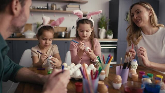 Caucasian family of four people chatting and decorating easter eggs at home. Shot with RED helium camera in 8K   