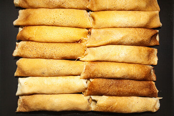 Fried and twisted pancakes stacked towards each other, top view.