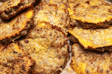 Several fried cutlets in egg batter in oil, top view.