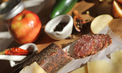 Peppercorn Salami on Tray With English and Irish Cheese, Sliced Apples and Spices in Rustic Kitchen