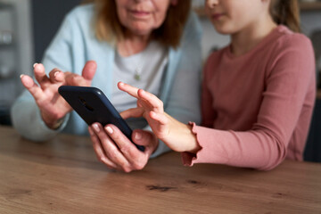 Close up of grandmother and her granddaughter using smart phone together