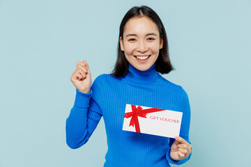 Young woman of Asian ethnicity 20s years old wears blue shirt hold gift certificate coupon voucher...