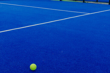 a ball on the surface of a blue paddle tennis court