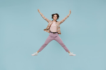Full body young excited exultant jubilant happy woman 20s wearing casual brown shirt jump high with outstretched hands legs isolated on pastel plain light blue background People lifestyle concept