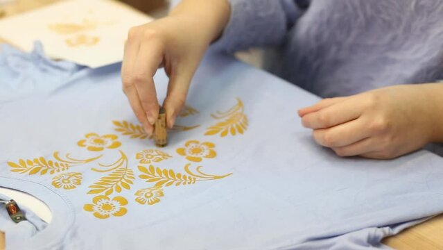 Hand-printed pattern on fabric. Print a picture on a blue T-shirt. Modern hobbies and creativity. Ancient traditions.