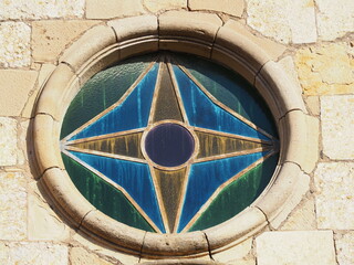 ventana circular con vidriera de cristal color azul y ocre formando dos estrellas con un gran ojo en el centro, iglesia de san salvador de vilanova de prades, tarragona, españa, europa  - obrazy, fototapety, plakaty