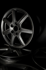 Grey rim of a light alloy wheel of a car on a black background general plan