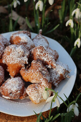 Traditional italian Fritters called Frittelle on a plate in a bunch of Snowdrops flowers