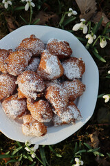 Traditional italian Fritters called Frittelle on a plate in a bunch of Snowdrops flowers