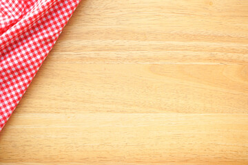 Wood table background with crumple pink plaid fabric or tablecloth in the corner 