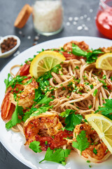 Stir fry noodle with shrimps, lemon and fresh parsley on white plate, soba with prawns, asian cuisine, top view