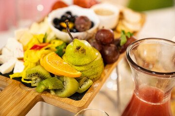 wooden tray with appetizers, fruits and sauces. cheese, olives, grapes, pear, tomato and mayonnaise sauce for the buffet. Catering.