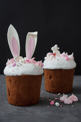 Glazed easter cake decorated with bunny ears cookies, sugar icing and meringues on dark background, copy space. Happy Easter holidays.  Kulich
