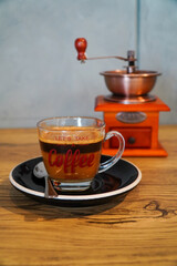 Portrair photo of milk coffee served in a clear cup and coffee grinder background